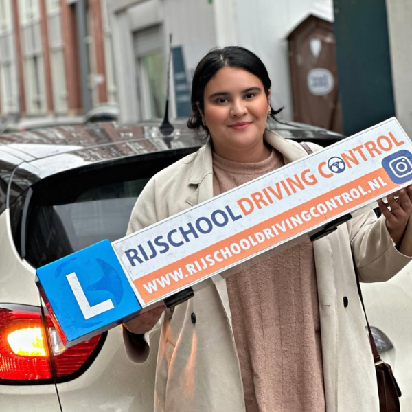 Geslaagde leerling viert zijn rijbewijs met een grote glimlach na een geslaagde bij haar rijbewijs halen in Rotterdam