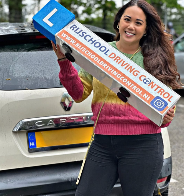 Trots poseert een geslaagde dame na het behalen van haar rijbewijs in Rotterdam.