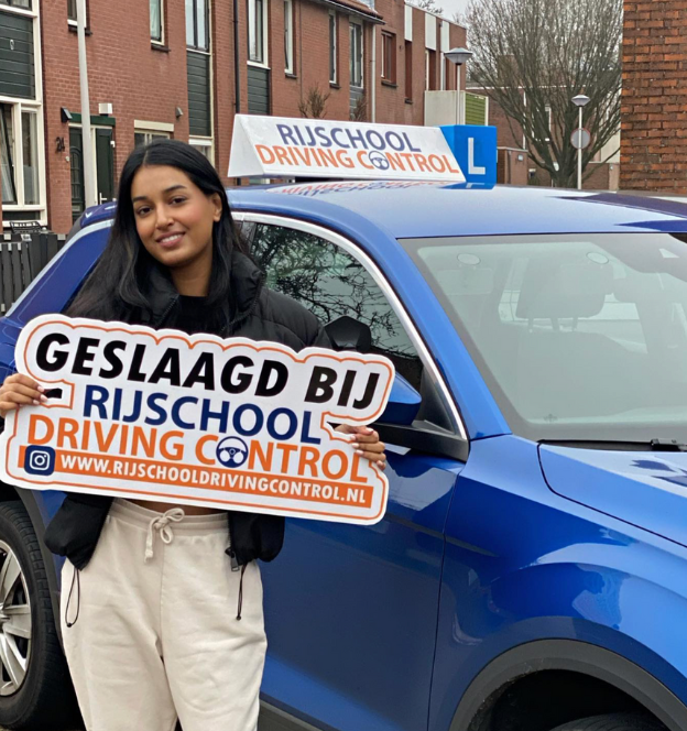 Blije geslaagde leerling houdt rijbewijs omhoog na succesvolle rijles in Rotterdam.