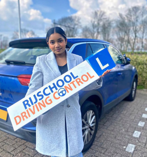 Geslaagde leerling met automaat-rijbewijs in Rotterdam, blij met rijbewijs in de hand voor de lesauto van Rijschool Driving Control