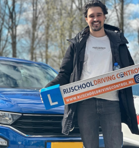 Geslaagde leerling bij onze rijschool in Schiedam toont trots zijn rijbewijs na een succesvolle rijopleiding.