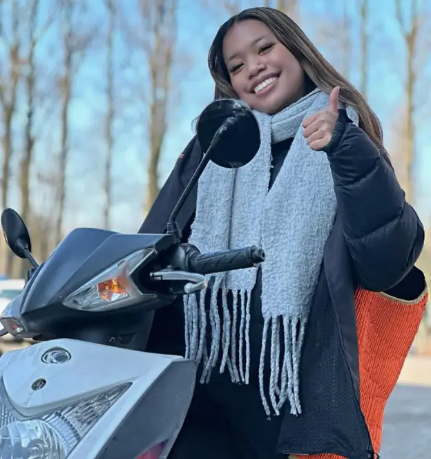 Leerling poseert met scooter na behalen rijbewijs in Rotterdam