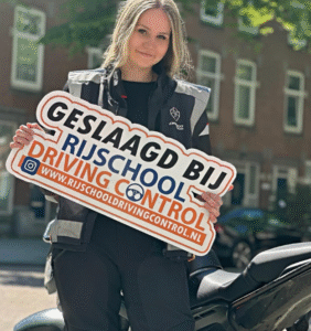 Geslaagde leerling na het behalen van het AVD motor examen in Rotterdam, trots met motor en instructeur